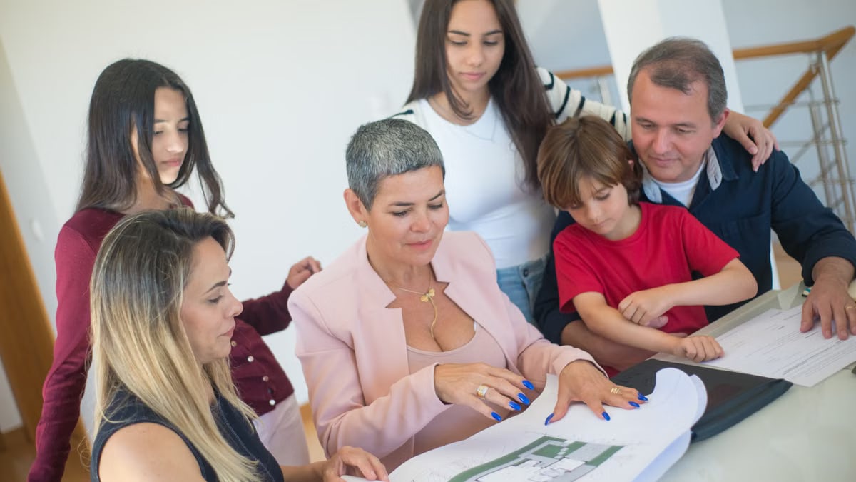 A family discusses property plans with a realtor indoors, focused on purchasing a new home.